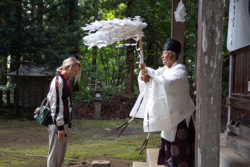 Tourist being blessed by a Shinto priest at a temple in Nagano, Japan